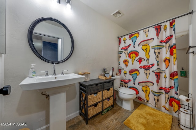 bathroom featuring curtained shower, wood-type flooring, and toilet