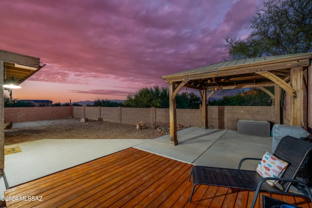 deck at dusk featuring a gazebo and a patio