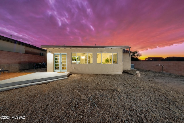 back house at dusk featuring a patio area and french doors