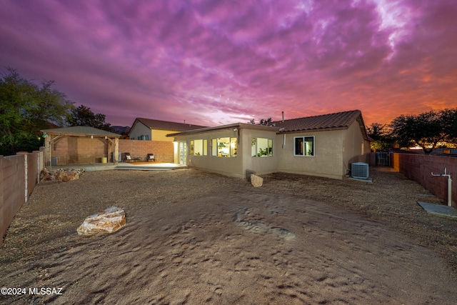 back house at dusk featuring a patio area and central air condition unit