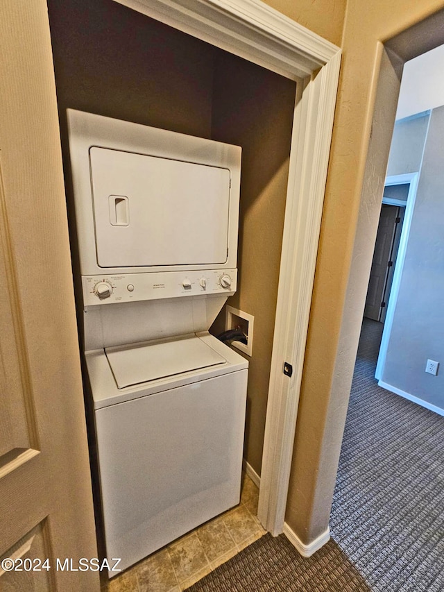 clothes washing area featuring laundry area, stacked washer and clothes dryer, and baseboards