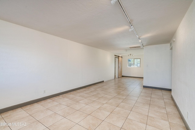 empty room featuring light tile patterned floors, a textured ceiling, and rail lighting