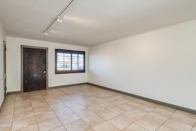 spare room featuring a textured ceiling and light tile patterned floors