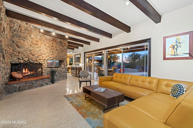 living room featuring beam ceiling and a stone fireplace