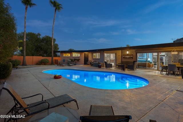 pool at dusk featuring a patio