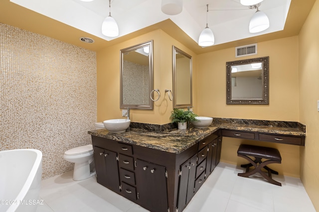 bathroom with tile patterned flooring, toilet, a bathtub, vanity, and tile walls