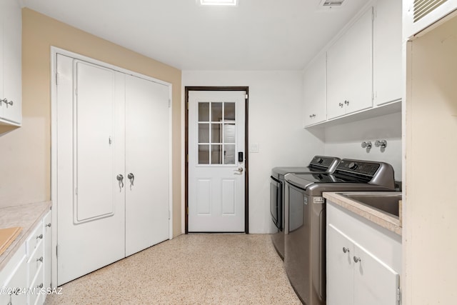 clothes washing area featuring washing machine and dryer and cabinets