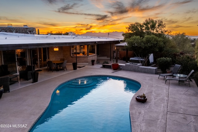 pool at dusk with a patio area