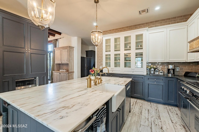 kitchen featuring visible vents, a sink, light stone counters, a chandelier, and stainless steel appliances