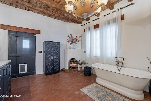 full bathroom with a freestanding tub, brick floor, a lit fireplace, and beam ceiling