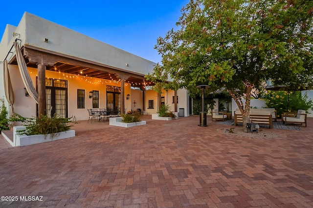 rear view of property featuring a patio, an outdoor living space, french doors, and stucco siding