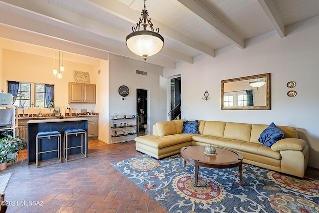 living area with brick floor, beam ceiling, and visible vents