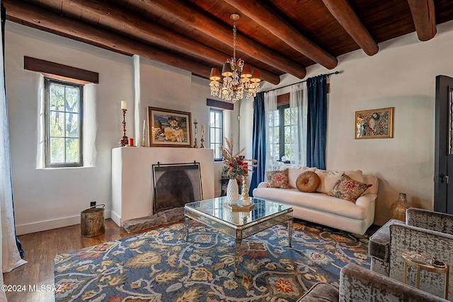 living room with wood finished floors, beamed ceiling, a fireplace with raised hearth, wooden ceiling, and a notable chandelier