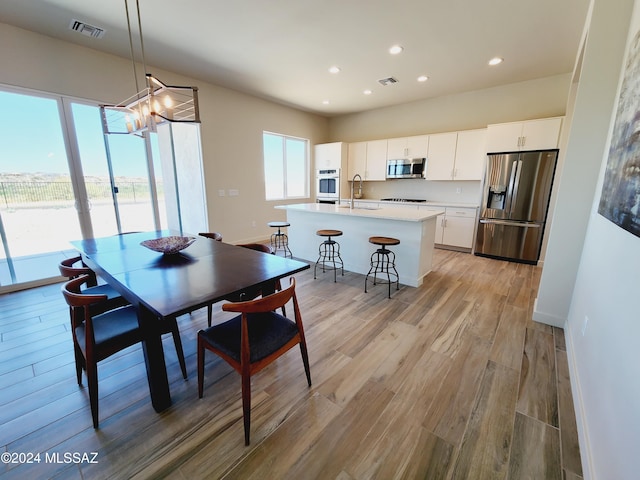 dining space featuring light hardwood / wood-style flooring, a notable chandelier, and sink