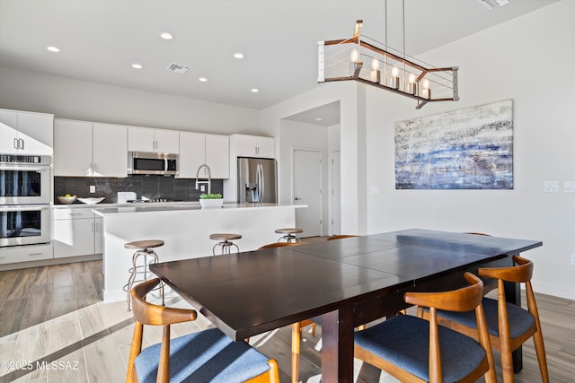 dining area with recessed lighting, visible vents, and light wood finished floors