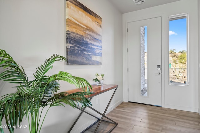 foyer entrance with light wood-type flooring, visible vents, and baseboards