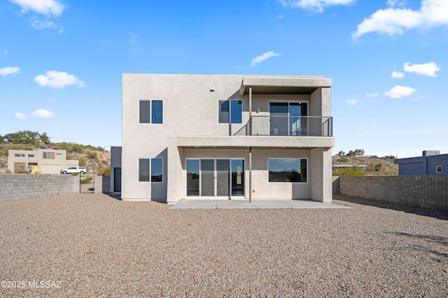 back of property with a balcony, a patio area, a fenced backyard, and stucco siding