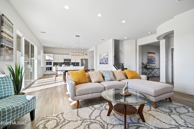 living room with visible vents, baseboards, light wood-style flooring, stairway, and recessed lighting