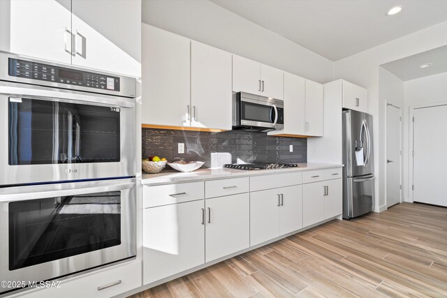 kitchen featuring white cabinets, light stone countertops, light wood-type flooring, and appliances with stainless steel finishes