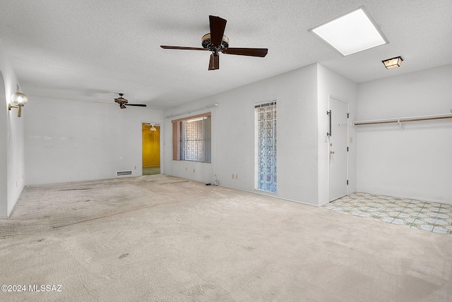 interior space featuring ceiling fan, a textured ceiling, and light colored carpet