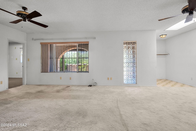 empty room featuring a textured ceiling, carpet floors, and ceiling fan