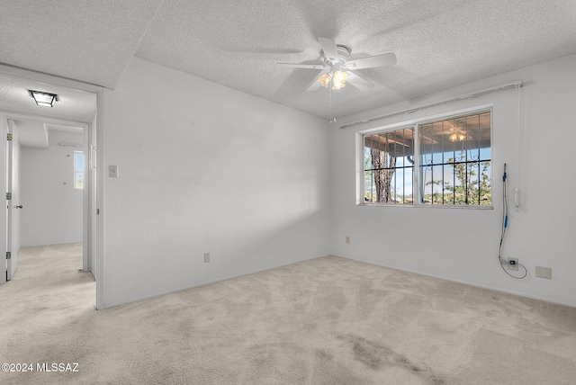 empty room featuring light carpet, a textured ceiling, and ceiling fan