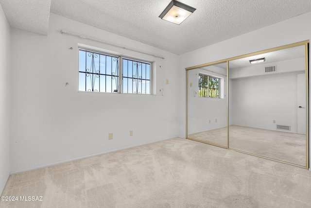 unfurnished bedroom with a closet, a textured ceiling, and light colored carpet