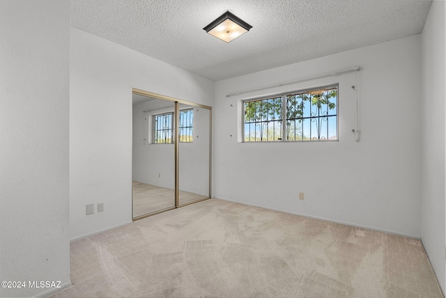 unfurnished bedroom featuring a closet, a textured ceiling, and light colored carpet