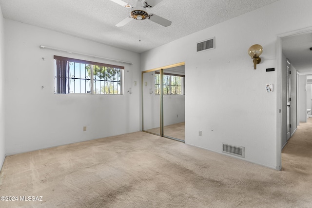 empty room with light carpet, a textured ceiling, and ceiling fan