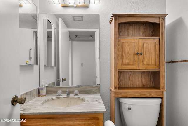 bathroom with vanity, toilet, and a textured ceiling