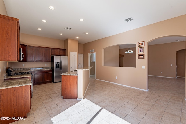 kitchen featuring light stone counters, light tile patterned floors, an island with sink, sink, and stainless steel appliances