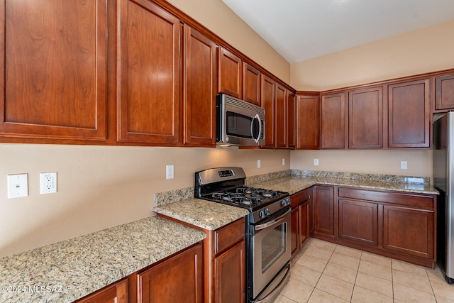 kitchen featuring light stone counters, stainless steel appliances, and light tile patterned floors