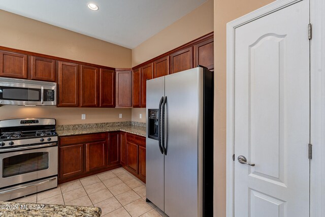 kitchen with stainless steel appliances, light stone counters, and light tile patterned floors