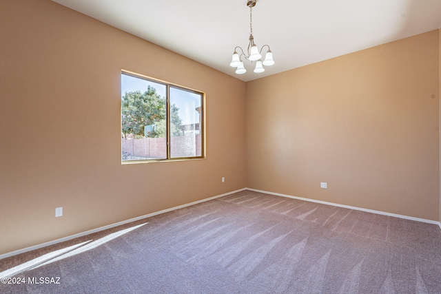 carpeted spare room with a chandelier