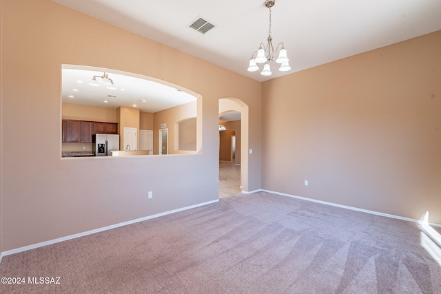 empty room with an inviting chandelier and light colored carpet