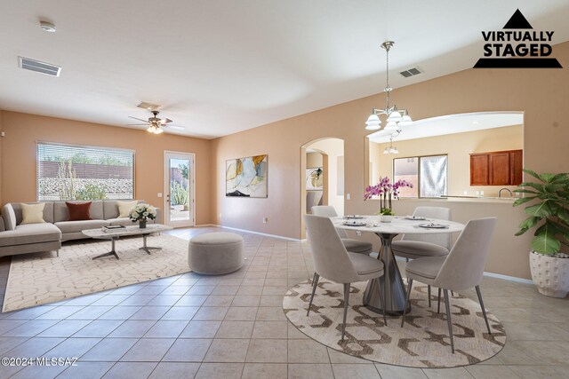 tiled dining room with ceiling fan with notable chandelier