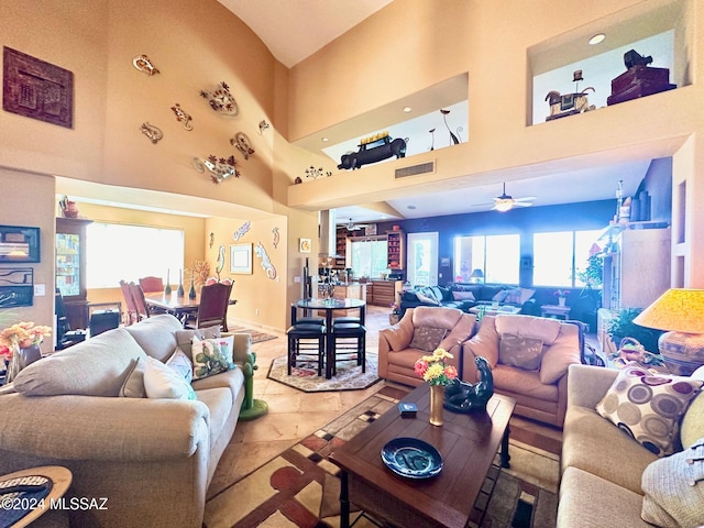 living room featuring a towering ceiling, ceiling fan, and light tile patterned flooring