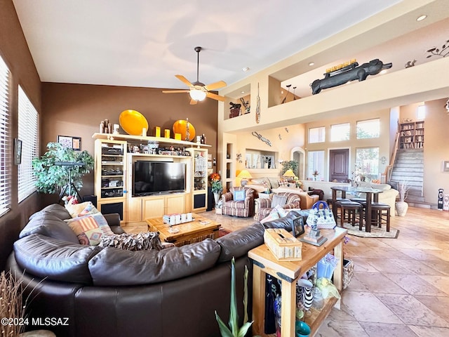 living room with ceiling fan, a healthy amount of sunlight, and a high ceiling