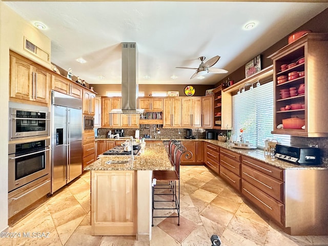 kitchen featuring island exhaust hood, backsplash, a breakfast bar, built in appliances, and an island with sink