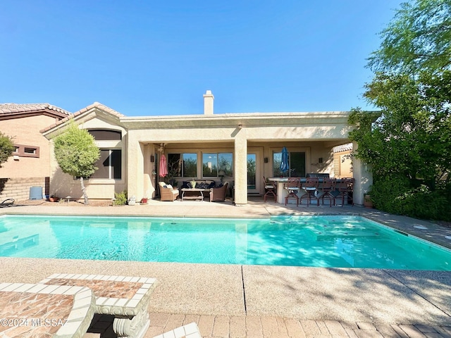 view of pool with outdoor lounge area, a bar, and a patio