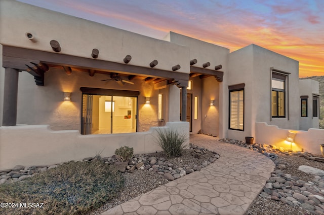 back house at dusk featuring ceiling fan