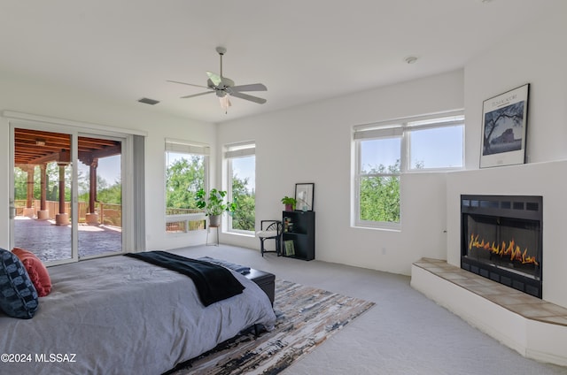 carpeted bedroom with ceiling fan, a fireplace, and access to exterior