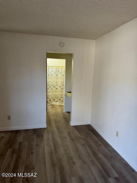 empty room featuring dark hardwood / wood-style floors and a textured ceiling