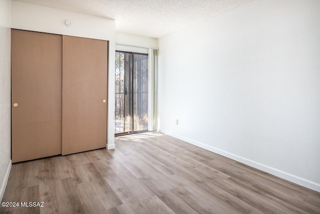 unfurnished bedroom featuring a closet, a textured ceiling, and light hardwood / wood-style flooring