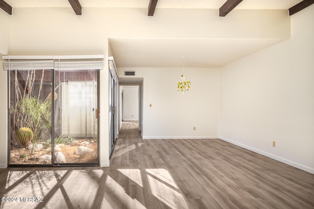 spare room featuring hardwood / wood-style flooring, a healthy amount of sunlight, beamed ceiling, and a chandelier