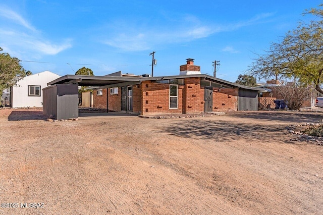 back of property with brick siding and a chimney
