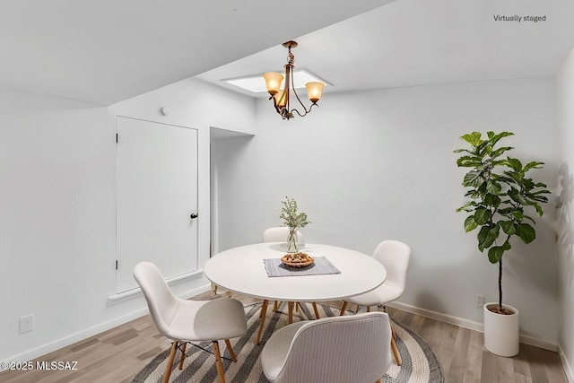 dining area with baseboards, an inviting chandelier, and light wood-style floors