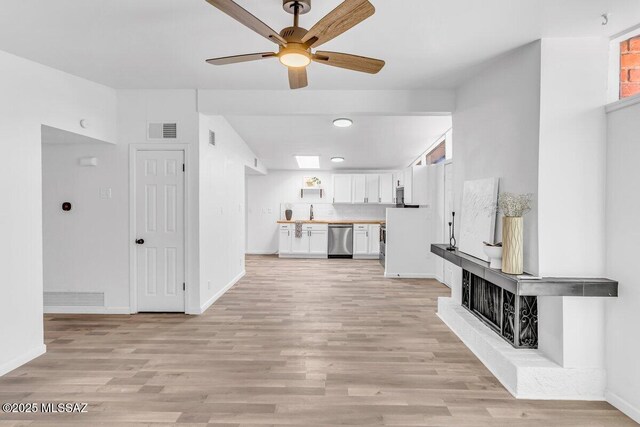 unfurnished living room with visible vents, light wood-style flooring, and baseboards