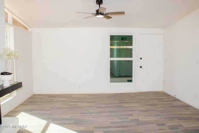 empty room featuring ceiling fan, baseboards, and wood finished floors