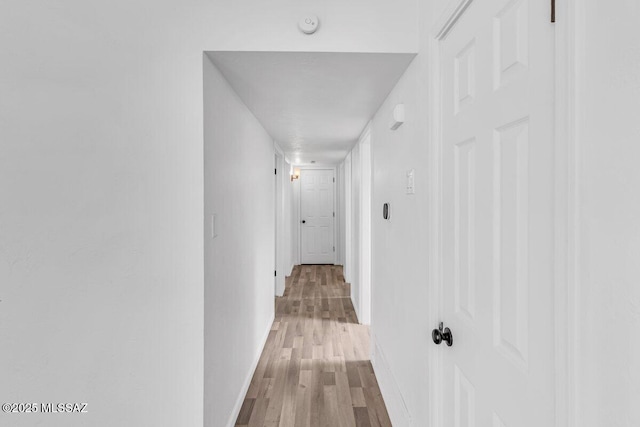 hallway featuring baseboards and wood finished floors